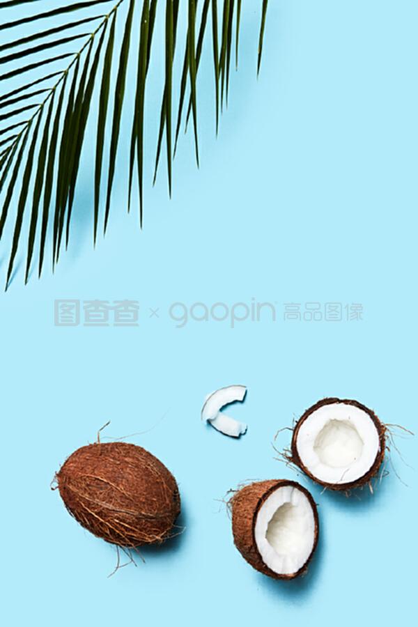 一片椰子和整個(gè)椰子,在藍(lán)色背景上有一片棕櫚綠葉。食物成分。平鋪。一個(gè)由有機(jī)的一半和一個(gè)椰子組成的美麗組成的藍(lán)色背景裝飾著一塊飾板,上面有一片平鋪。